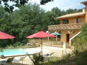 una casa y una piscina con sombrillas en la clairiere en Sarlat-la-Canéda