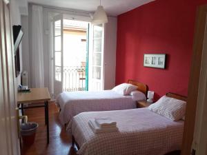 two beds in a room with a red wall at Pensión Manoli in Bilbao