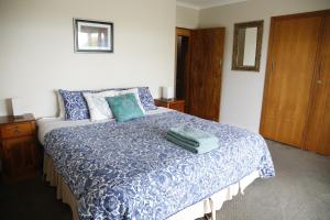 a bedroom with a blue and white bed with pillows at Beachside Entertainer in Apollo Bay