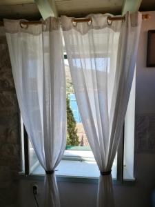 a window with white curtains in a room at Buena Vis-ta Apartments with the Sea View in Vis