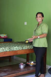 a woman is standing next to a bed at Taman Sandat in Amed