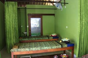 two beds in a room with green walls and a mirror at Taman Sandat in Amed