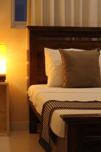 a bedroom with a bed with a wooden headboard and pillows at Araliya Suite in Nugegoda