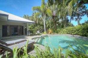 una piscina junto a una casa con árboles en Tranquility By The Course Port Douglas, en Port Douglas