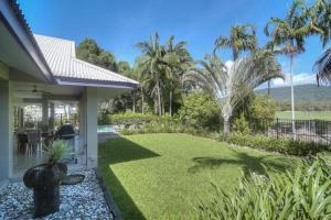 un patio con césped y palmeras en Tranquility By The Course Port Douglas, en Port Douglas