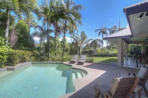 a swimming pool in a yard with palm trees at Tranquility By The Course Port Douglas in Port Douglas