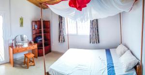 - une chambre avec un lit à baldaquin et un bureau en bois dans l'établissement Villa A.TIA, à Morondava