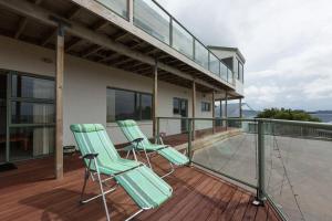 dwa zielone krzesła siedzące na balkonie domu w obiekcie Ocean View B&B w mieście Whitianga