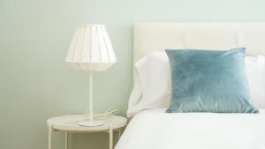 a bed with a blue pillow and a lamp on a table at HQ Rooms Apartments San Vicente in Valencia