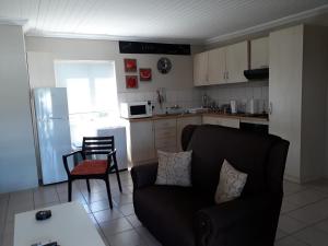a living room with a couch and a kitchen at The Upper Deck Apartment in Swellendam