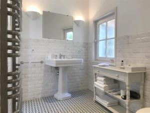 a white bathroom with a sink and a mirror at Le Clos Saluces in Avignon