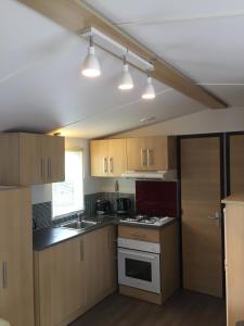 una cucina con mobili in legno e un forno a piano cottura di Mobil home 6 pers, 3 ch, Kerlann**** Bretagne Sud a Pont-Aven