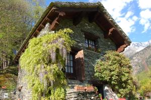 a stone house with flowers growing around the windows at Chalet La Baita in Baceno