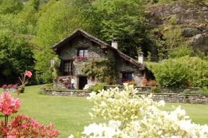 a small stone house with flowers in the yard at Chalet La Baita in Baceno