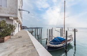 威尼斯的住宿－CA' DEI SCORZERI，停靠在建筑物旁边的码头的船只