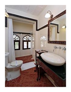a bathroom with a sink and a toilet and a mirror at Rohet Garh in Rohat