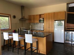 a kitchen with a white refrigerator and white bar stools at Apostle Hideaway - Central Port Campbell in Port Campbell