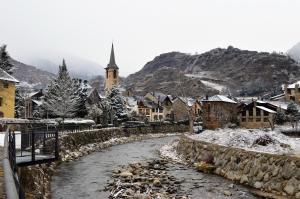 a village in the snow with a river at Apartament Esterri Centre in Esterri d'Àneu