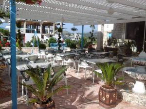 a patio with tables and chairs and palm trees at Vip Apartment by "Murati" in Ksamil