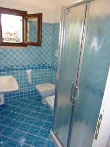 y baño de azulejos azules con aseo y ducha. en Appartamento in residence fronte mare, en Murta Maria