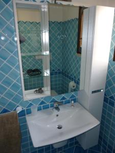 Baño de azulejos azules con lavabo y espejo en Appartamento in residence fronte mare en Murta Maria