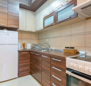 cocina con armarios de madera y nevera blanca en Apartment Kiki, en Zlatibor