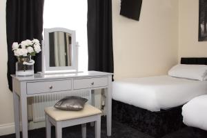 a bedroom with a bed and a dresser with a mirror at Castle Park Hotel in Leicester