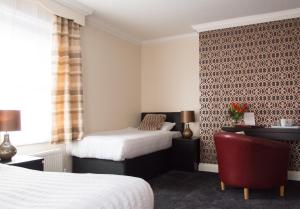 a hotel room with two beds and a red chair at Castle Park Hotel in Leicester