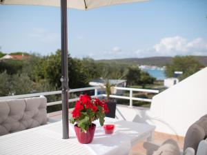 a table with a vase of red flowers on a balcony at SunnyHomePunta in Sukošan