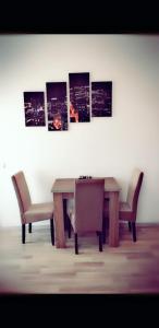 a dining room table with two chairs and a table and some paintings at Niko Apartment in Mamaia