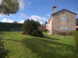 une vieille maison en pierre sur un champ herbeux dans l'établissement Casa Socorro, à A Estrada