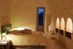 um quarto com uma cama numa parede de pedra em Masseria Camarda em Ceglie Messapica