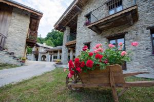 um carrinho de mão de madeira cheio de flores em frente a um edifício em Il Sogno Della Vita AgriResort - Country Rooms & Suites em Peveragno