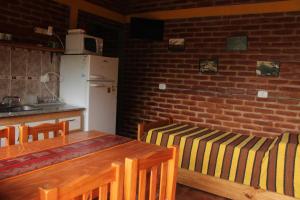 cocina con mesa, sillas y pared de ladrillo en La Posada Del Poeta en Mina Clavero