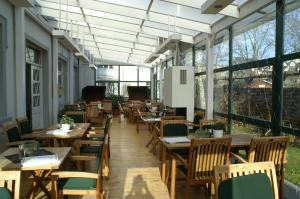 un restaurante con mesas y sillas de madera y ventanas en Hotel Strandpavillon en Baabe