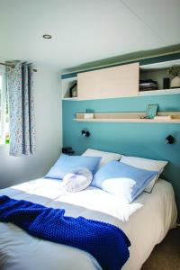 a large bed with blue and white pillows on it at Camping Le Ventadour in Meyras