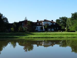 a house with a reflection in the water at Leśny Dworek Winnica Darłowo in Darłowo