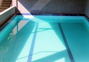 a swimming pool with a reflection of a shadow in the water at Apartments Kovačić in Makarska