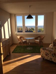 a living room with a table and chairs and windows at Alpenpanorama am Hochrhein in Gailingen