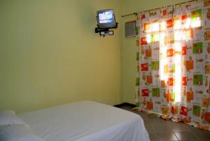 ein Schlafzimmer mit einem Bett und einem Fernseher an der Wand in der Unterkunft Pousada Sereia Dourada in Itacaré