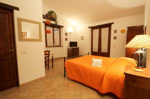 パッシニャーノ・スル・トラジメーノにあるCasa Il Leccinoのベッドルーム1室(オレンジ色の毛布付きのベッド1台付)