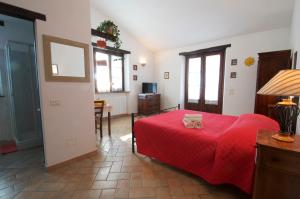 パッシニャーノ・スル・トラジメーノにあるCasa Il Leccinoの赤いベッドと猫が置かれたベッドルーム1室