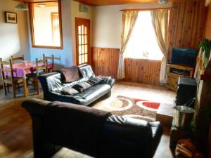 uma sala de estar com um sofá de couro e uma mesa em The Old School House em Clifden