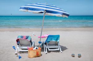 twee stoelen en een parasol op het strand bij Hotel Palme Gemelle in Vieste