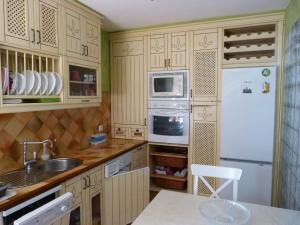 eine Küche mit Holzschränken und einem weißen Kühlschrank in der Unterkunft Appartement Punta Almina 100 m from t h e sea in San Luis de Sabinillas