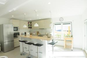 a kitchen with a refrigerator and a counter with stools at LV Premier Meco/Lagoa LA1 in Sesimbra