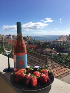 un plato de fresas y una botella de vino y una copa en Atlantis Apartment, en Câmara de Lobos
