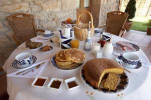 una mesa con un mantel blanco con un desayuno de panqueques y pan en Casa do Mudo, en Cervo