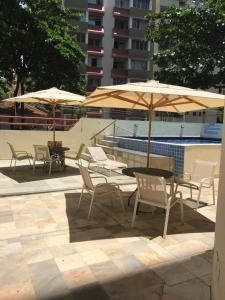 un grupo de mesas y sillas con sombrillas junto a una piscina en Apart Rei Barra, en Salvador