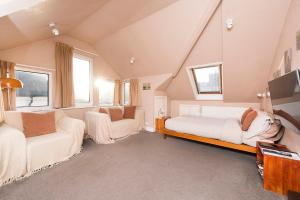 um quarto com duas camas, um sofá e janelas em Great Loft & Location by Belsize Park tube em Londres